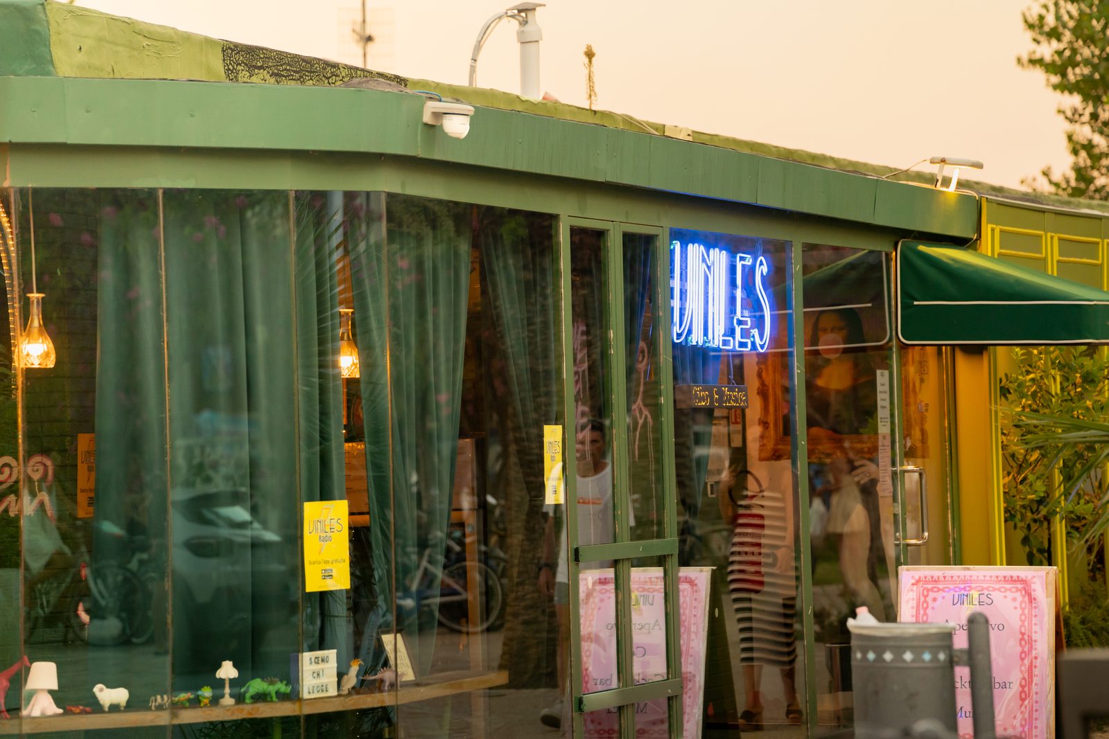 La facciata verde di Viniles con l'insegna al neon accesa