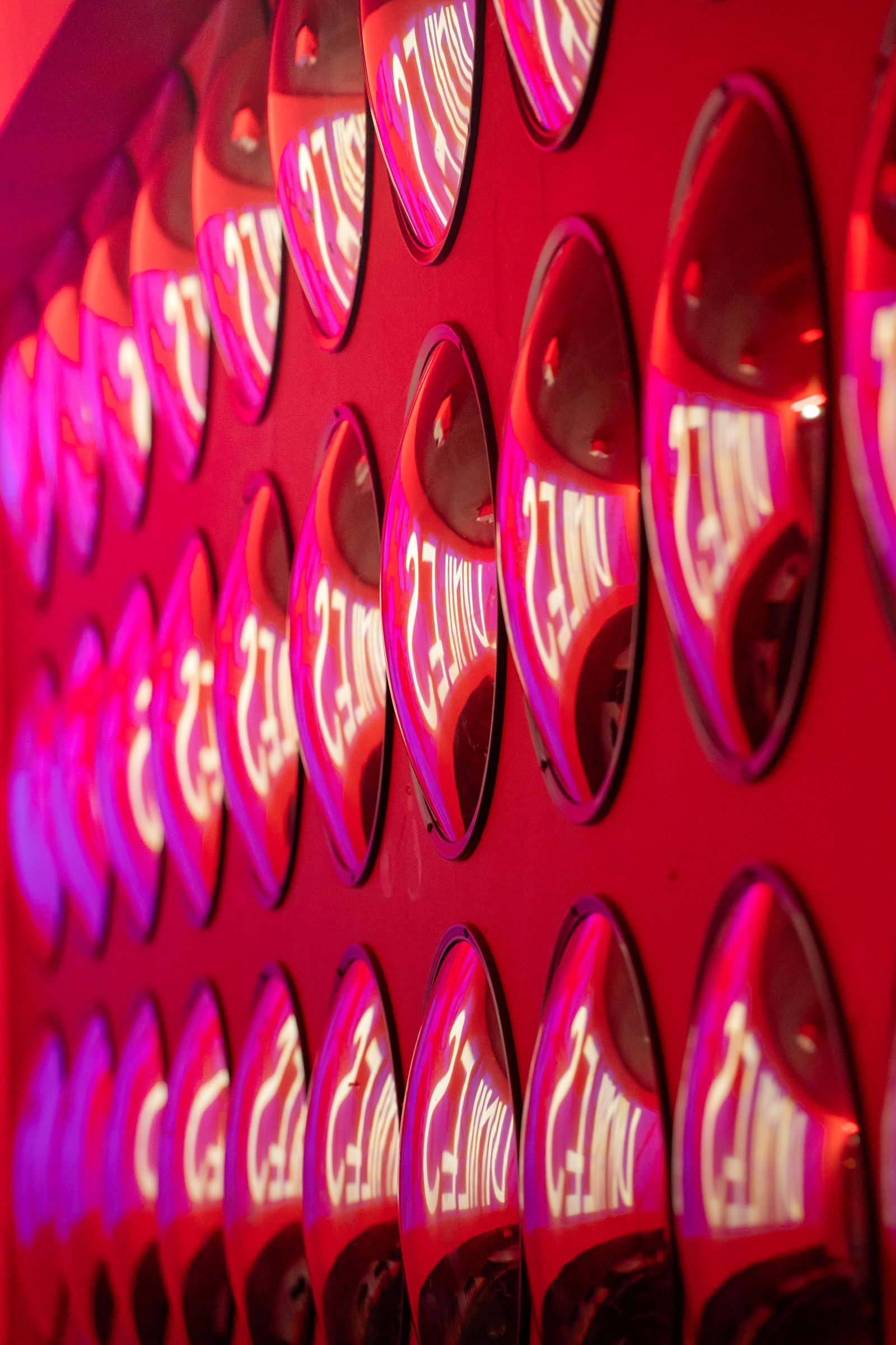 La parete di specchi ovali illuminata di rosa